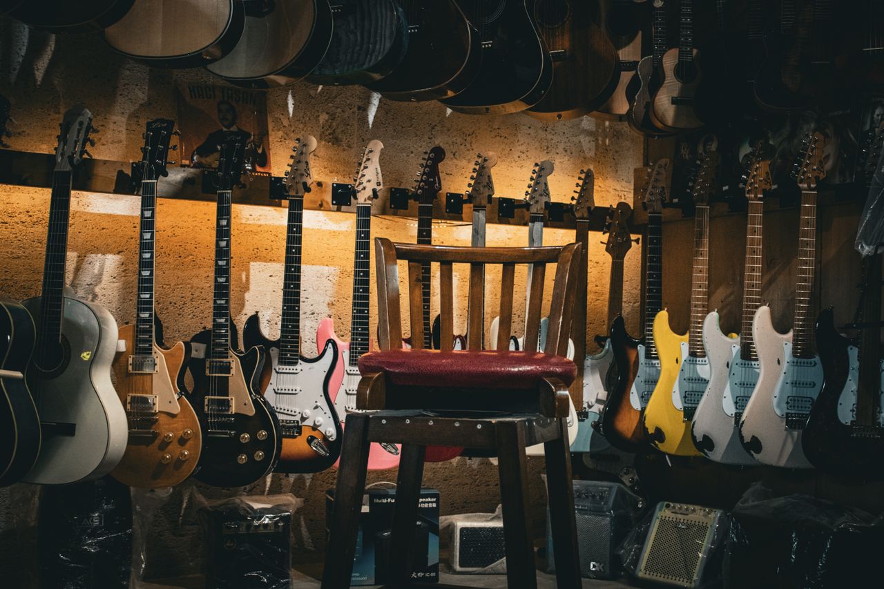 Services A cozy music store with a variety of guitars on display and a single chair in the center.