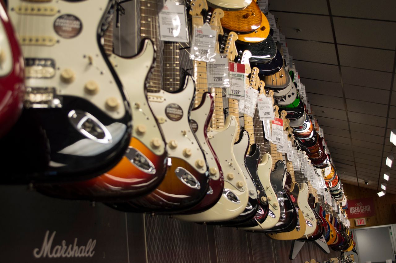 Mastering the First Impression: Your intriguing post title goes here Row of colorful electric guitars hanging in a music store, showcasing diverse models and prices.
